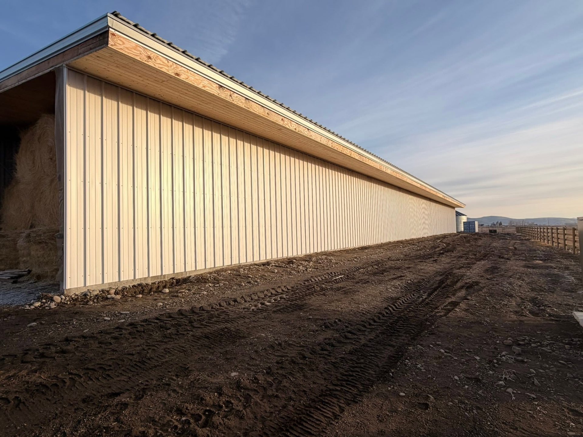 Long metal-clad agricultural building at sunset